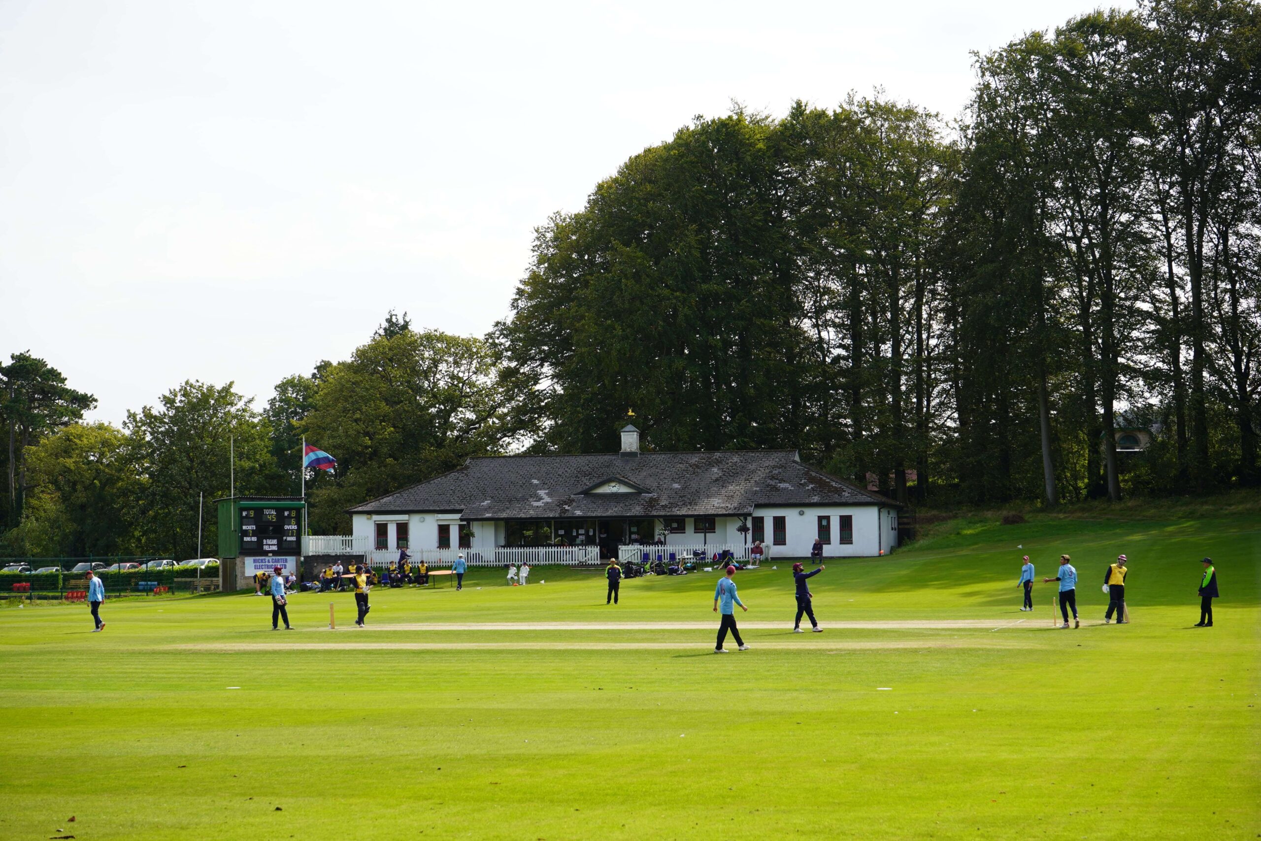 Cricket players playing a game in front of a white club house