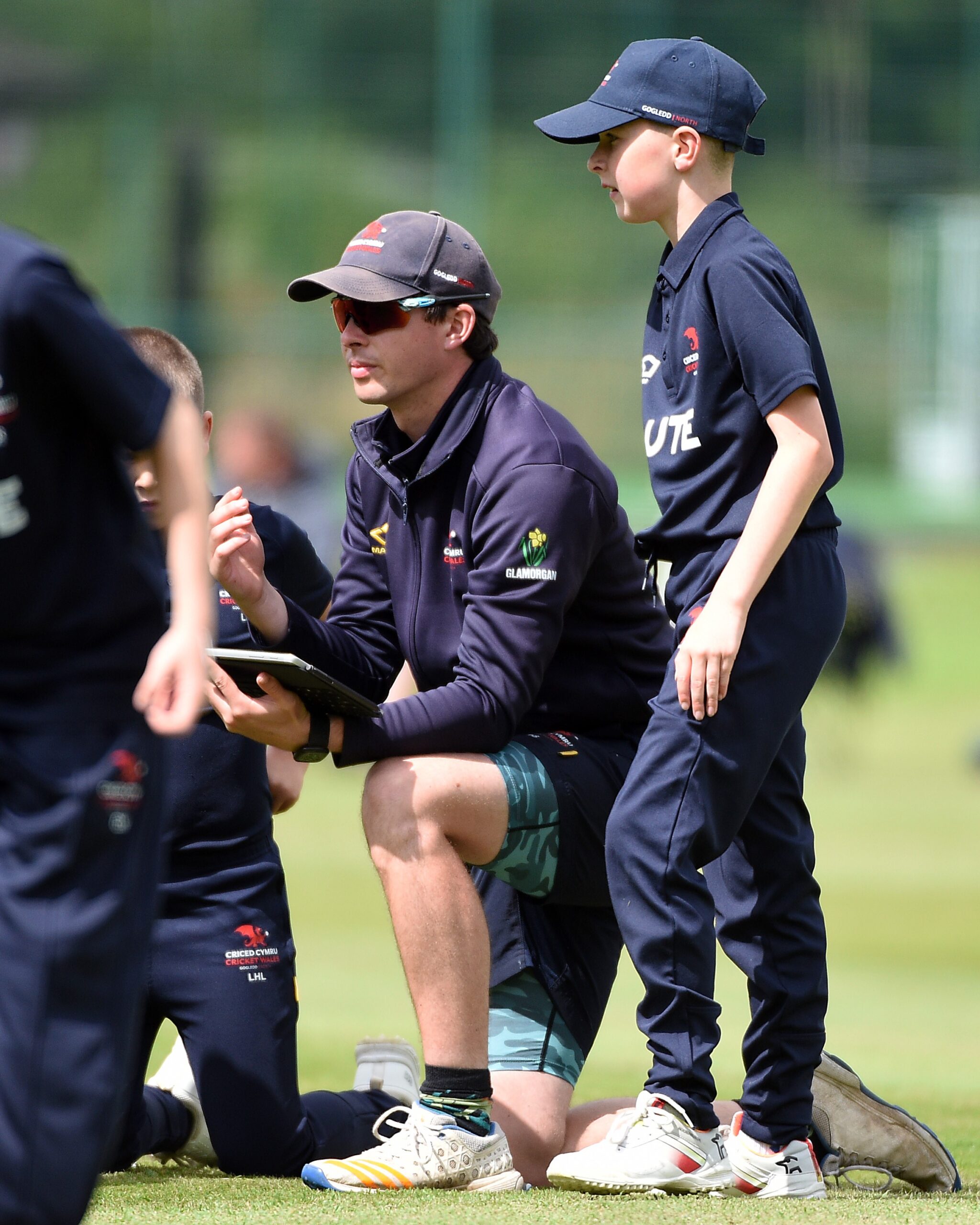 Child in Cricket Wales polo, listening to a man in Glamorgan County Cricket Club jacket